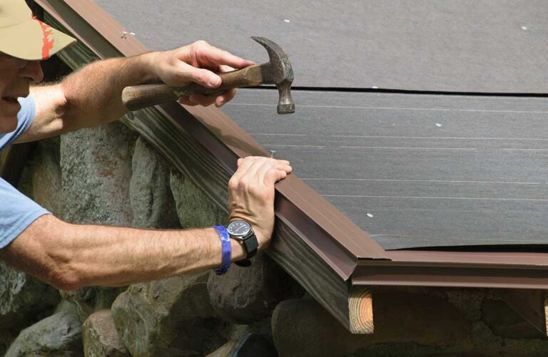 Homeowner examining roof shingles, flashing, gutters, and attic ventilation on a snowy residential house.