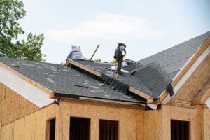A homeowner examines attic insulation near roof rafters and ventilation channels.