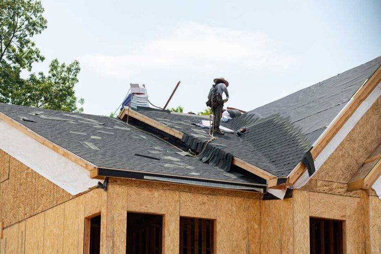 A homeowner examines attic insulation near roof rafters and ventilation channels.