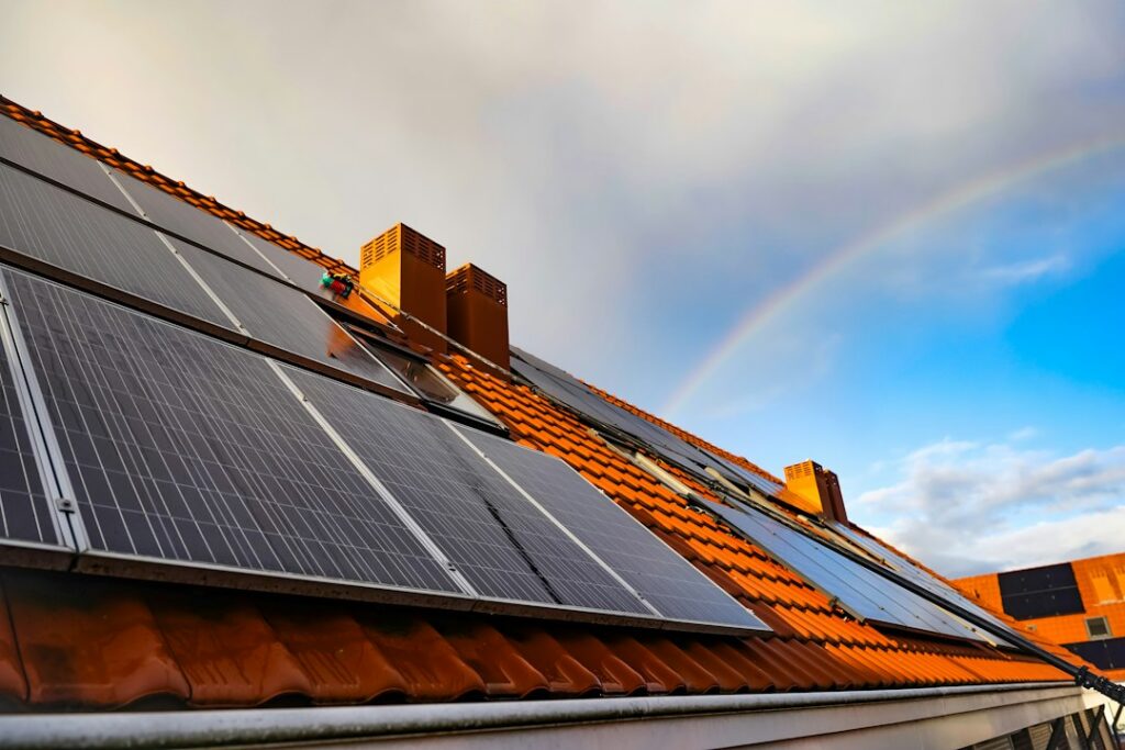Solar panels mounted on a residential shingle roof with snow nearby and visible roof flashing.